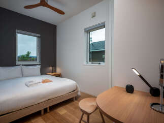 Experience modern comfort in this beautifully appointed bedroom, featuring a plush queen-sized bed with crisp white linens and two inviting pillows.
