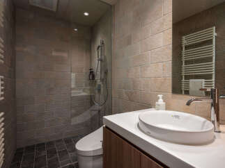 Experience modern luxury in this beautifully appointed bathroom, featuring a spacious walk-in shower with elegant tilework and a sleek, wall-mounted shower system.