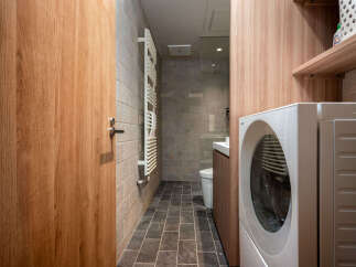 Discover this modern bathroom and laundry space, featuring a sleek wooden door and coordinating cabinetry.
