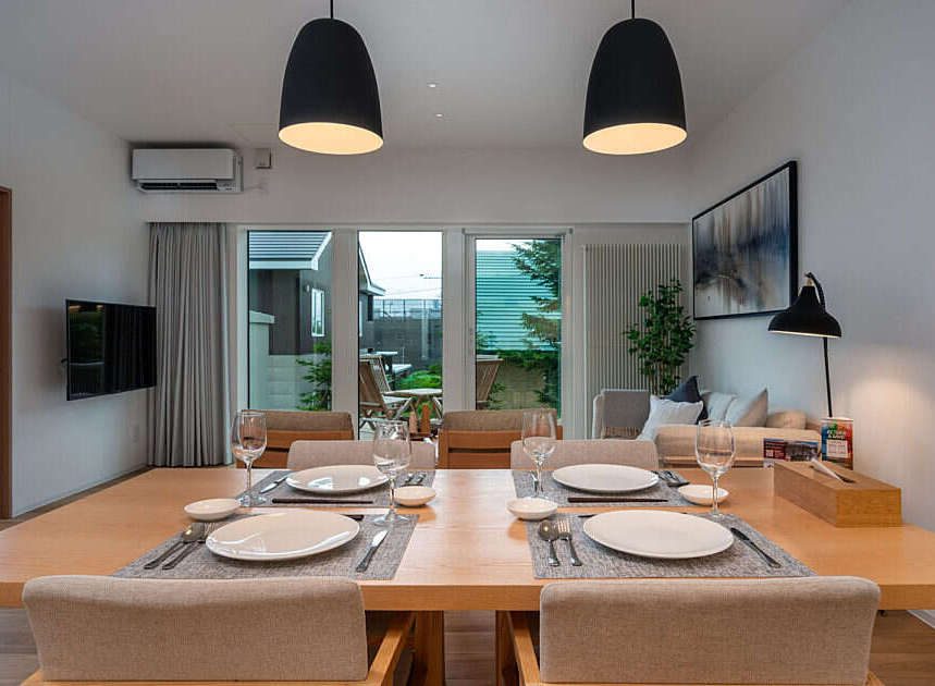 Experience modern living in this beautifully appointed dining area, featuring a spacious wooden table set for four and elegant pendant lighting.