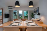 Experience modern living in this beautifully appointed dining area, featuring a spacious wooden table set for four and elegant pendant lighting.