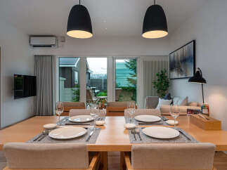 Experience modern living in this beautifully appointed dining area, featuring a spacious wooden table set for four and elegant pendant lighting.