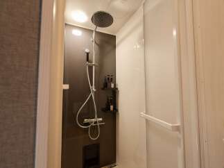 Experience modern comfort in this bathroom featuring a sleek shower with a rainfall showerhead and a handheld wand for a customizable experience.