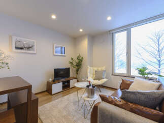 Experience modern living in this stylish apartment, featuring a comfortable living area with a plush sofa and a cozy armchair perfect for relaxation.