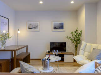 Experience modern living in this stylish apartment, featuring a dedicated dining area with a wooden table and bench, perfect for intimate meals.