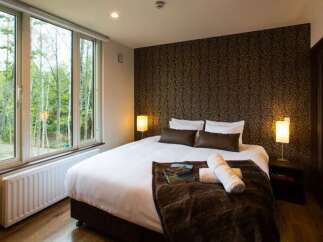 Experience serene living with this beautifully appointed bedroom, featuring a large window that offers picturesque views of lush greenery.