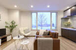 Experience modern living in this beautifully appointed apartment, featuring a spacious living area with a comfortable brown leather sofa and a stylish accent chair.