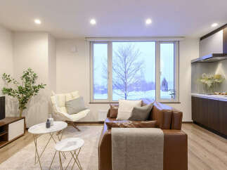 Experience modern living in this beautifully appointed apartment, featuring a spacious living area with a comfortable brown leather sofa and a stylish accent chair.