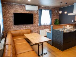 Experience modern living in this stylish apartment featuring a cozy L-shaped leather sofa and a sleek wooden dining table, perfect for intimate meals.