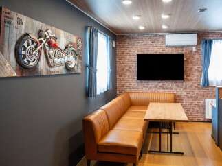 Experience modern living in this stylish apartment featuring a comfortable brown leather sectional sofa and a sleek wooden dining table.