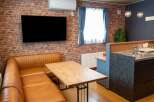Experience modern living in this stylish apartment featuring a spacious L-shaped leather sofa and a rustic brick accent wall.