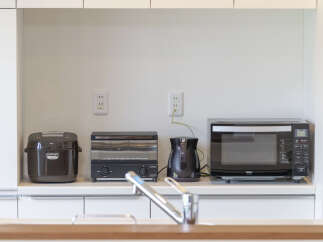 This modern kitchen features a sleek countertop with essential appliances, including a rice cooker, toaster oven, electric kettle, and a Haier microwave.