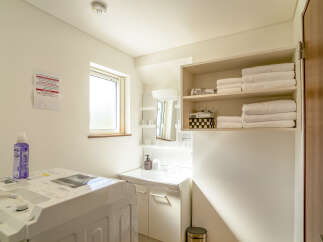 Discover a well-equipped laundry area featuring a modern washing machine and ample storage for towels and toiletries.