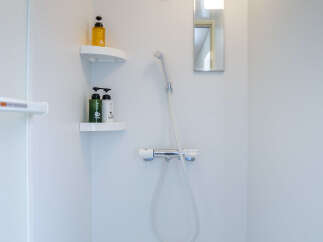 Experience a refreshing start to your day in this modern shower featuring a convenient corner shelf for your toiletries.