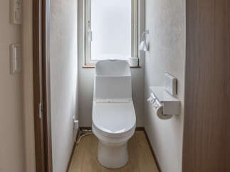 This modern bathroom features a sleek white toilet with a bidet function, complemented by a frosted window for natural light and privacy.