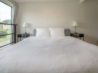 Experience comfort and style in this beautifully appointed bedroom, featuring a plush king-sized bed with crisp white linens and two elegant bedside lamps.