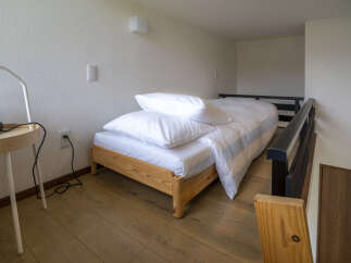 Discover this cozy loft bedroom featuring a comfortable single bed with crisp white linens and plush pillows.