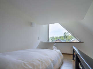 Experience serene living in this charming attic bedroom, featuring a comfortable bed dressed in crisp white linens and a plush pillow.