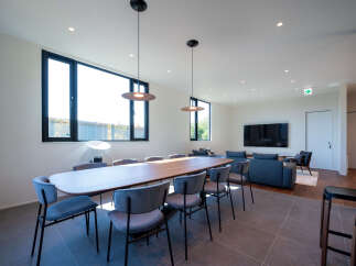 Experience modern living in this spacious open-plan area, featuring a large dining table perfect for gatherings and a comfortable lounge area with a sleek television.