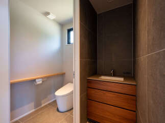This modern bathroom features a sleek, wall-mounted toilet with a wooden shelf and toilet paper holder for convenience.