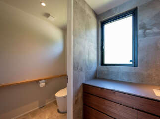 Discover modern elegance in this bathroom, featuring a sleek vanity with rich wood cabinetry and a minimalist integrated sink.