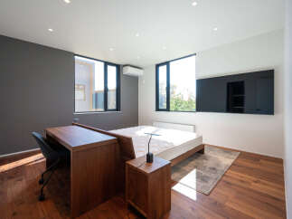 This modern bedroom features a sleek wooden desk and chair, perfect for a home office setup.