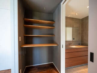Discover this modern home featuring a spacious walk-in closet with elegant wooden shelves, perfect for organizing your belongings.