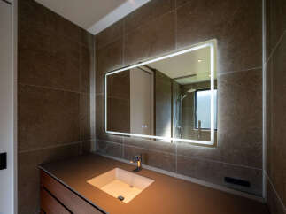 Experience modern luxury in this stunning bathroom, featuring a sleek vanity with an integrated sink and a large, illuminated mirror.