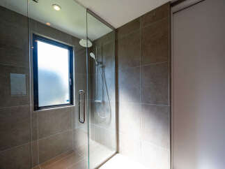 Experience modern luxury in this bathroom featuring a sleek glass-enclosed shower with a rainfall showerhead and handheld wand.