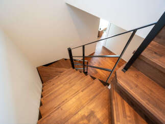 Experience modern living with this stunning staircase featuring rich wooden treads and a sleek black metal railing.