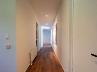 Step into this inviting hallway featuring a sleek white radiator and a modern thermostat on the left wall.
