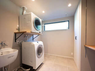 This modern laundry room features a stacked washer and dryer for space efficiency, complemented by a sleek sink and ample shelving.