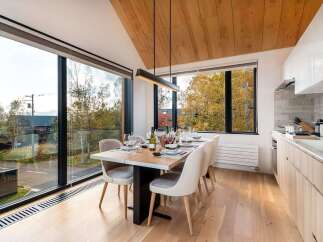 Experience modern living in this stunning dining area, featuring a sleek table set for six and large windows that flood the space with natural light.