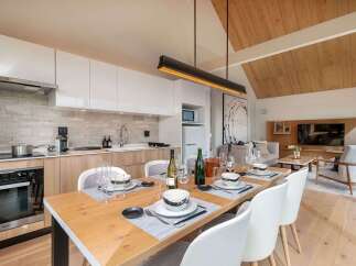 Experience modern living in this beautifully appointed dining and kitchen area, featuring sleek white cabinetry and a stylish stone backsplash.