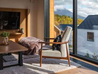 Experience breathtaking mountain views from this cozy living space, featuring a comfortable armchair perfect for relaxation.