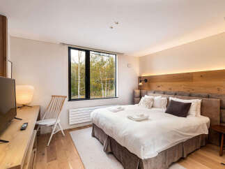 Experience ultimate comfort in this beautifully appointed bedroom, featuring a plush king-sized bed and a large window offering serene views of the surrounding nature.