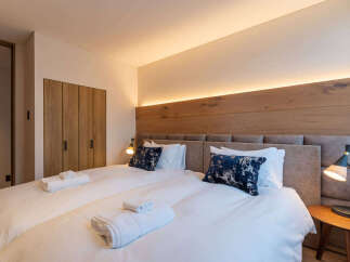 Experience ultimate comfort in this beautifully appointed bedroom, featuring two plush twin beds dressed in crisp white linens and adorned with stylish navy accent pillows.