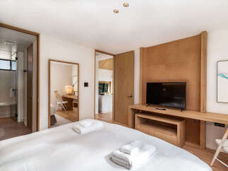 Experience modern comfort in this beautifully appointed bedroom, featuring a plush bed with crisp white linens and neatly folded towels.