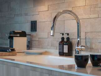 This modern kitchen features a sleek chrome faucet and a textured tile backsplash, creating a sophisticated look.