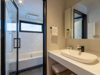 Experience modern comfort in this well-appointed bathroom, featuring a sleek bathtub and a spacious vanity with a contemporary sink.