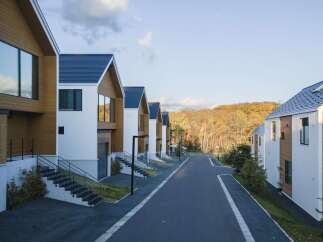 Discover modern living in this stunning row of contemporary homes, featuring sleek white exteriors accented with warm wood paneling and dark blue roofs.