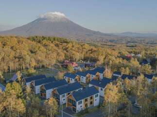 Discover modern living nestled amidst the vibrant autumn foliage with a majestic mountain backdrop.
