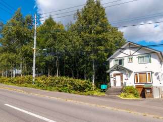 Discover this charming white house nestled amidst lush greenery and mature trees, offering a serene retreat.