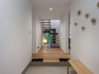 Step into this modern entryway featuring a sleek wooden staircase and a minimalist aesthetic.