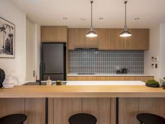 Experience modern living in this sleek kitchen featuring warm wood cabinetry and a striking mosaic tile backsplash.