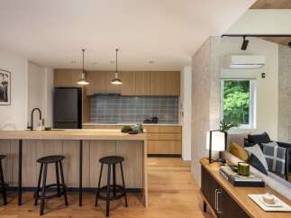 Experience modern living in this beautifully designed open-concept space, featuring a sleek kitchen with natural wood cabinetry and a stylish island breakfast bar.