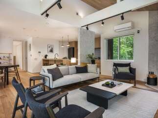 Experience modern living in this beautifully designed open-concept space, featuring a sleek living area with a comfortable sofa and stylish armchairs, perfect for relaxation.