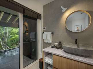 Experience modern luxury in this stunning bathroom featuring a unique stone vessel sink and a sleek wall-mounted faucet.