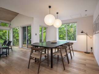 Experience modern living in this stunning dining area, featuring a sleek dark wood table surrounded by elegant wooden chairs with woven seats.