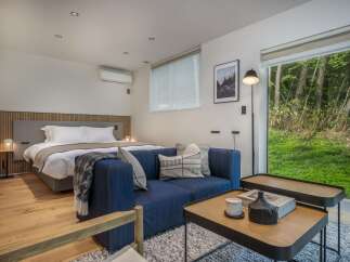 Experience serene living in this modern bedroom suite, featuring a comfortable king-sized bed and a plush blue sofa perfect for relaxation.